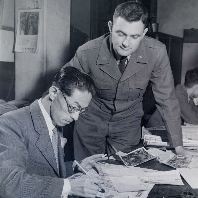 Soldier watches Japanese civilian fill out paperwork