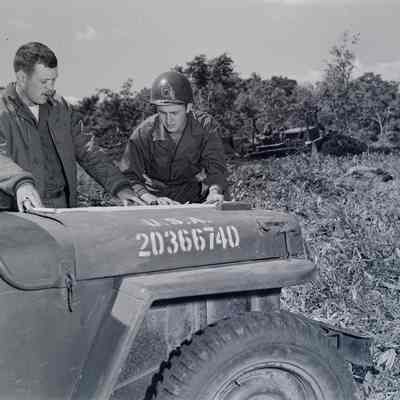 Soldiers examining a map on the hood of a Jeep