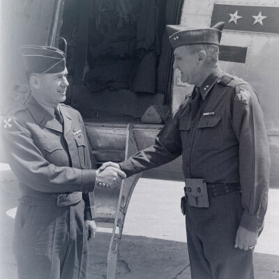 General Styron shaking hands with soldier next to transport aircraft
