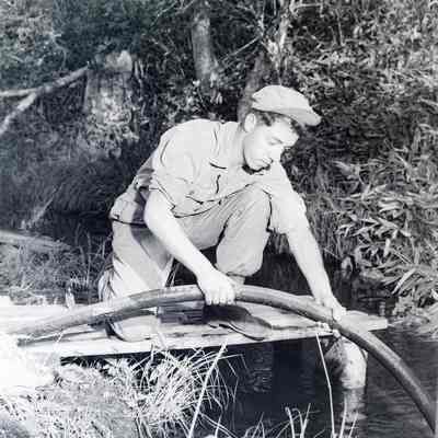 Soldier maneuvering a hose into a stream