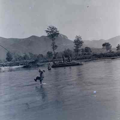 Soldier hanging on to wire above river