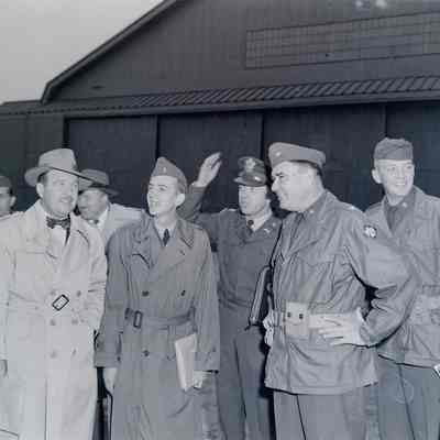 General Muldrow in front of an aircraft hangar with a civilian and several officers