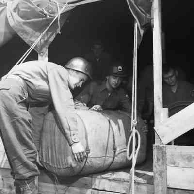 Soldiers putting large duffle bag into tent