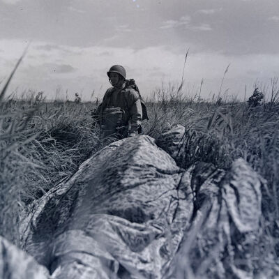Soldier with weapon and parachute in a field