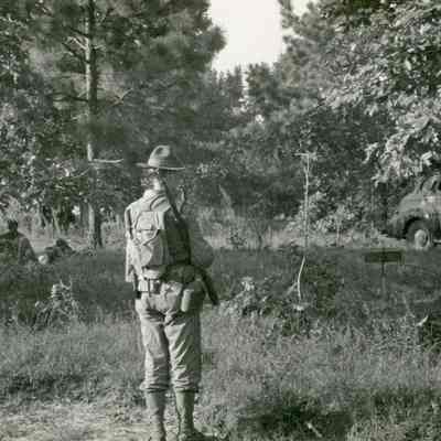 Soldier standing with rifle and equipment in the woods