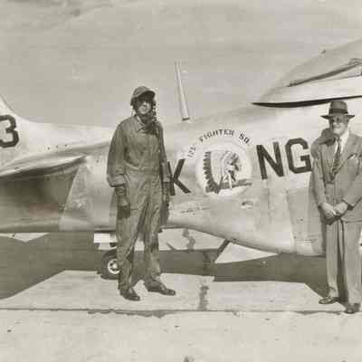 Two men pose in front of fighter plane
