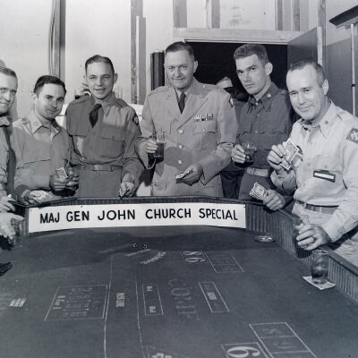 Several officers gathered around a craps table enjoying a drink and a little gambling