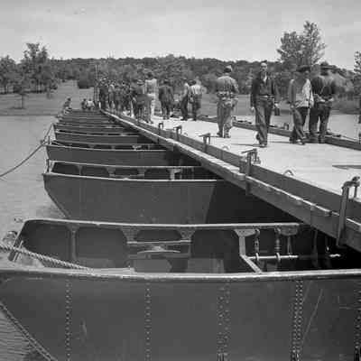 Soldiers walking across a pontoon bridge
