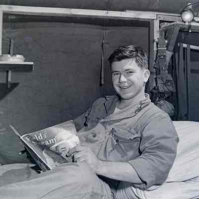 Soldier reading a magazine on his bunk in the barracks