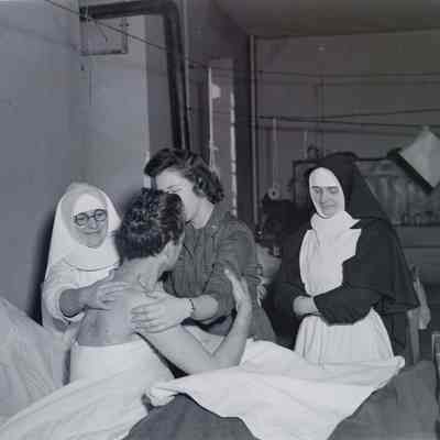 Nurse and nuns caring for wounded soldier