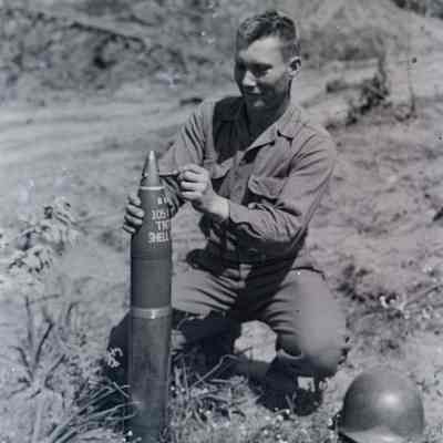 Soldier showing bullet pierced artillery shell