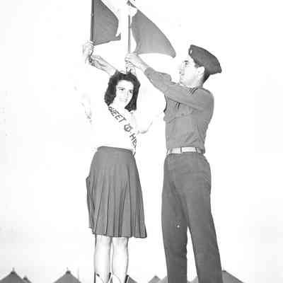 Soldier helping a woman wave signal flags