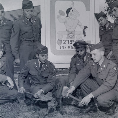 Native American soldiers burying a hatchet in front of sign for 279th Infantry