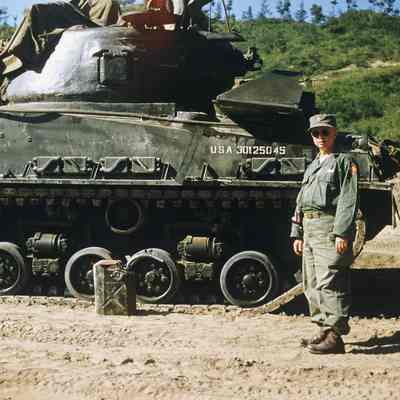 Chaplain posing next to a tank