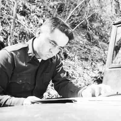Soldier studying a map on the hood of a jeep