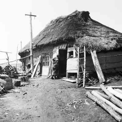 Soldier investigating a thatched roof hut