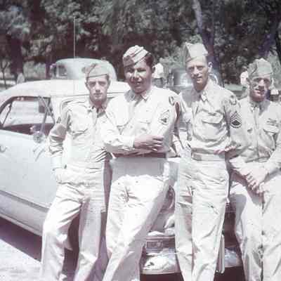 Soldiers posing in front of cars