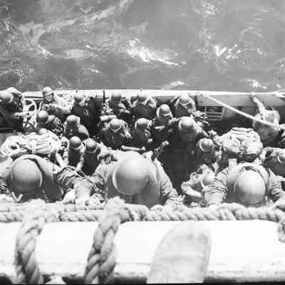 Soldiers climbing down nets into landing craft