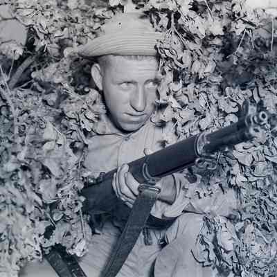 Soldier concealed in brush holding his rifle