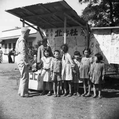 Soldier and group of children at a vendor's stall