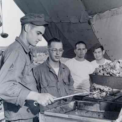 Soldier frying chicken in a field stove