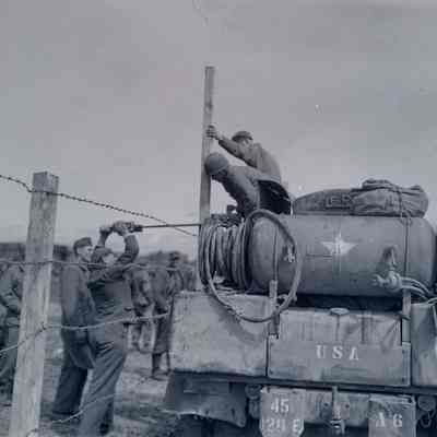 Soldiers and German prisoners working on a fence