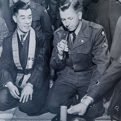 Soldier smoking with Japanese civilians