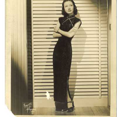 A Young Woman in a Black Embroidered Dress Posing in Front of a Screen
