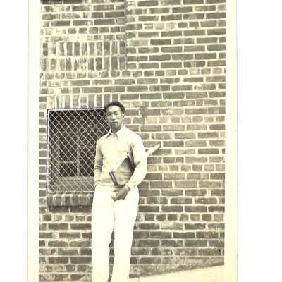 Man With Tennis Racket & Ball in Front of Brick Building