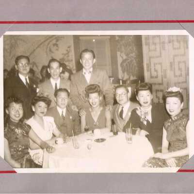 Three men stand behind five women and two men seated at a table