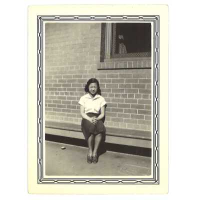 A Woman Posing for Photo Behind a Brick Building