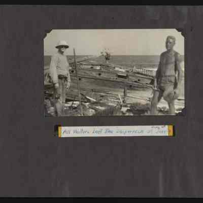 Two men stand in front of the shipwreck of the Amaranth on Jarvis Island