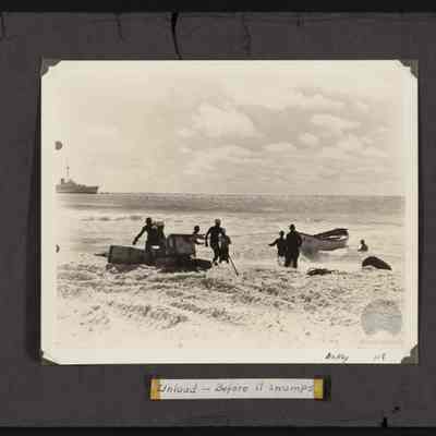 Men bringing supplies ashore unknown island