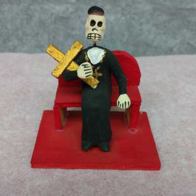 Miniature Priest sitting on a bench with a Cross
