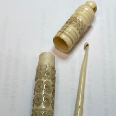#6: A two-piece bone case with circular carvings and a round top with a hole for a chatelaine or ribbon attachment. There is a hook to store inside