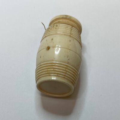 #1: A bone cotton barrel. Thread is wound around a central spindle inside the barrel, the end of the thread is pulled out of the hole on the side.