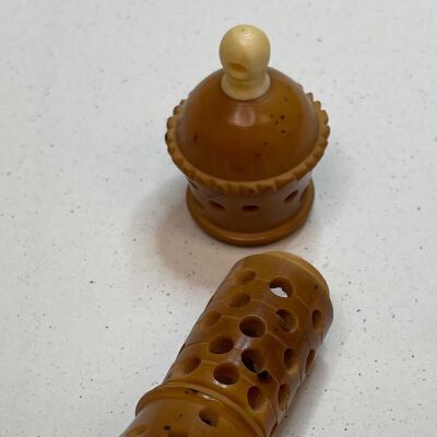 #8: A two-piece needlecase made of nut, possibly Tagua nut, the top has a bone finial with a hole for a ribbon attachment or may have had a Stanhope at one time. The dome of the top has a pie-crust edging with a short staff below with holes around the shaft. The tope screws onto the bottom. The bottom is a longer shaft with holes punched around the sides and mirrors the dome of the cap at the bottom with a dome shape surrounded by pie-crust edging.
