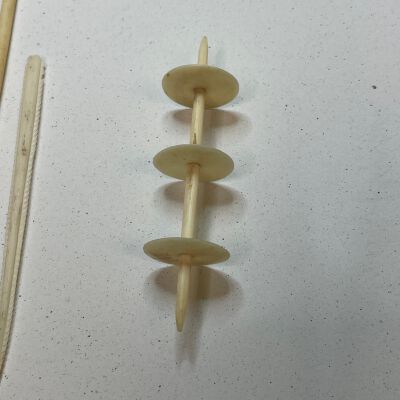 #4: Bone thread winder with three discs diving the center staff. The ends are pointed.