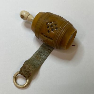 #3: A barrel-shaped tagua nut holder for a green silk measuring tape. A bone ring pull is attached to the end of the measuring tape and the spindle  with a Stanhope is also bone