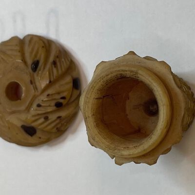 #2: A two-piece holder with a top and a bottom. The bottom is shaped like a basket and the top looks like a lid. there is a hole on the top of the lid and a matching circular inset in the interior base of the basket shape.