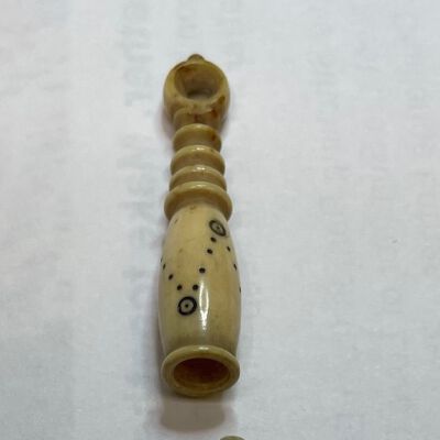 #4: A bone two-piece stiletto with a pattern of 'v' shapes on the shaft with the tip of each 'v' culminating in a circle with a dot inside. The longer handle piece has a carved spindle-shape arriving at a circular hole at the top which was either to thread a ribbon or may have had a Stanhope inserted. The half with the awl screws into the handle for working, or is covered by the shaft of the handle for storage