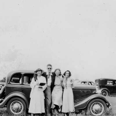 A group of four by a car