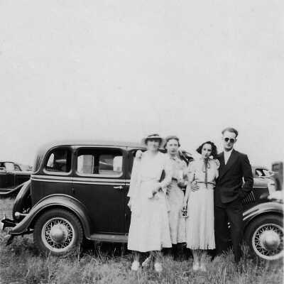 A group of four by a car