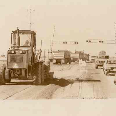 Tractor, Trucks & Cars on a Road Crossing Tracks