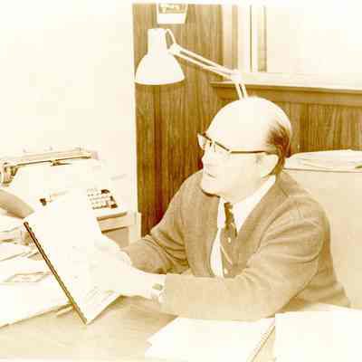 Man Sitting at Desk Pointing at Docments