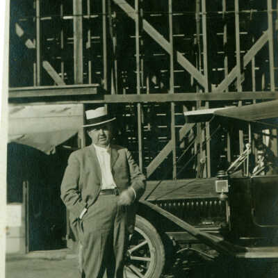 Man in front of construction and old car