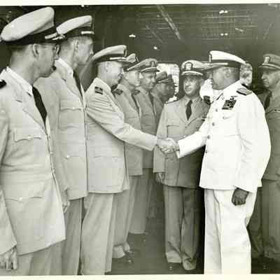 Captain McKechnie can be seen standing with Admiral "Jocko" Clark as they are welcomed by a line of officers. Admiral Clark shakes hands with a grinning officer.