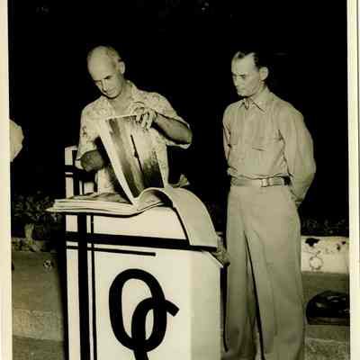 Captain Arnold McKechnie Looking through a Scrapbook at His Farewell Party