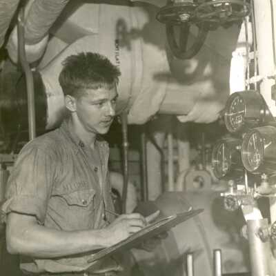 2019.06.48-4: A young man downstairs in the engine room taking notes on the equipment.