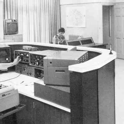 W1AW Maxim Memorial Station, cr. 1974. Equipment in use (on desk, from left): Hammarlund HQ-160 reciever, Hallicrafters HT-32B transmitter, Collins 75S-1 receiver, Hallicrafters SR-400 or SR-2000 transceiver, and unknown piece at right. Background: Sloping console with Collins S/Line, and (at right) home brew transmitters.: Image was isolated from a W1AW QSL card postmarked Oct 1974.